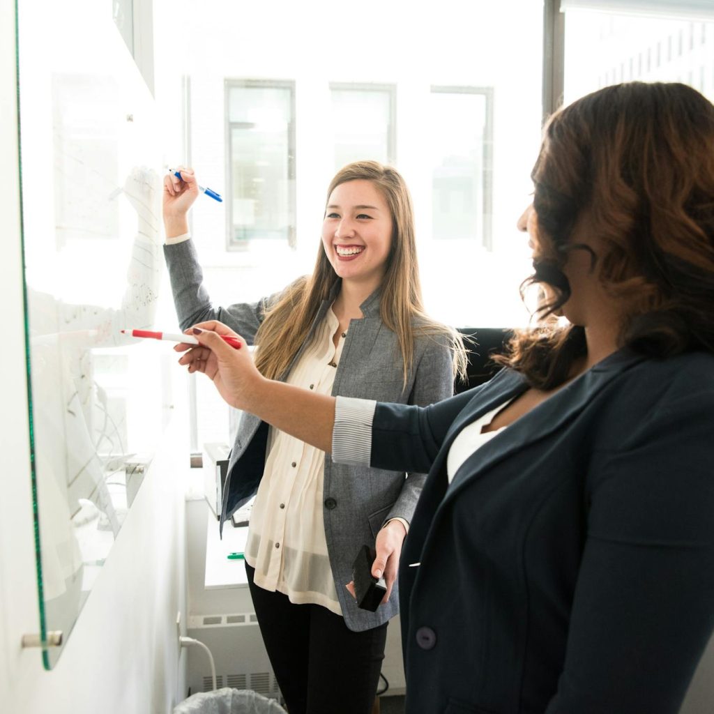 Two Women in Front of Dry-erase Board