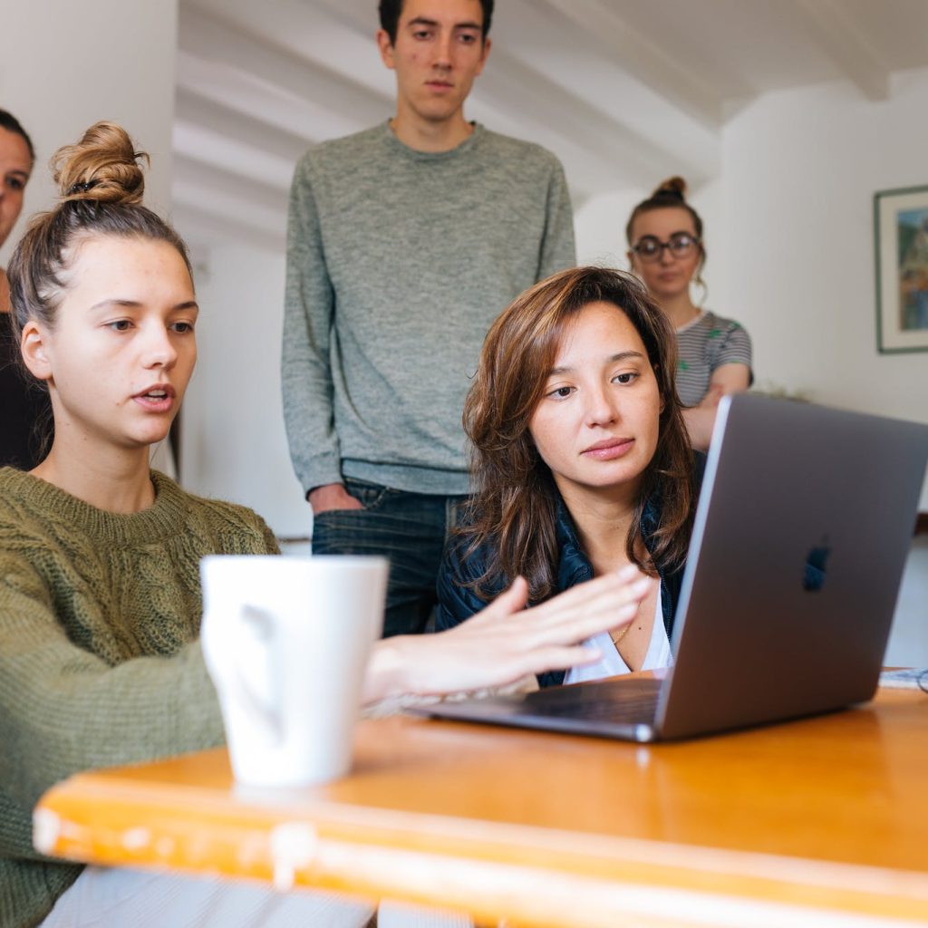 Woman In Green Top Using Macbook Beside Group Of People