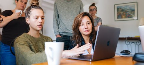 Woman In Green Top Using Macbook Beside Group Of People