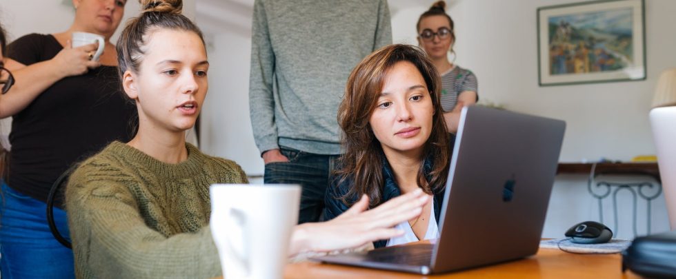 Woman In Green Top Using Macbook Beside Group Of People